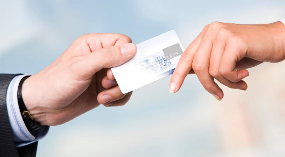 Close-up of transfer of credit card from maleís hand to that of female over blue background