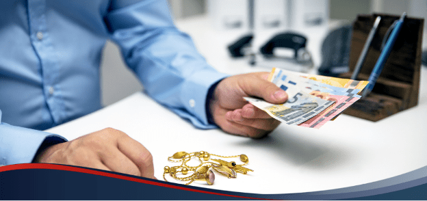 Person handing over bills for gold necklace on white table